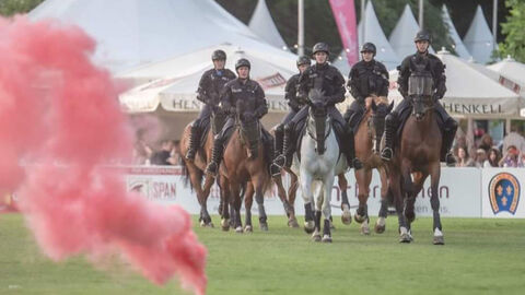 Angehörige der Polizeireiterstaffel reiten über eine Wiese auf eine Feuerquelle zu