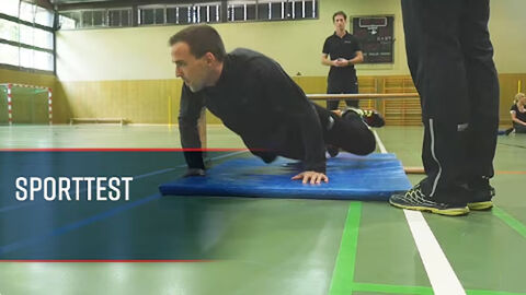 Ein Mann in Sportkleidung in einer Sporthalle stützt sich auf einer Matte ab.