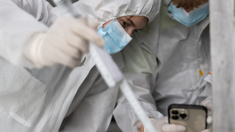 Zwei Beamte in Spurensicherungsanzügen fotografieren Spuren am Fenster