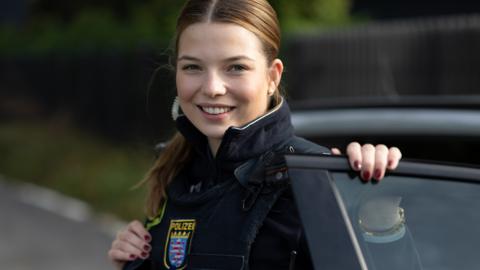 Schutzpolizisten steigt lächelnd aus Streifenwagen