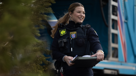 Polizistin mit Klemmbrett dokumentiert Unfallaufnahme