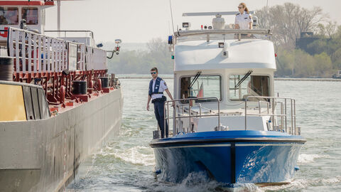 Polizist und Polizistin auf Polizeiboot kontrollieren ein Schiff