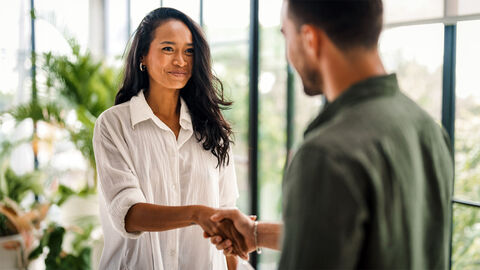 Zwei Personen stehen sich gegenüber und geben sich die Hand.