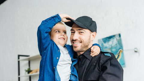 Vater mit Kind auf dem Arm beim Spielen.