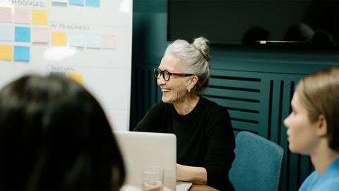 Mehrere Personen sitzen mit Laptops in einem Meeting.