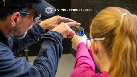 Ausbilder zeigt junger Person die richtige Handhabung einer Trainingswaffe.