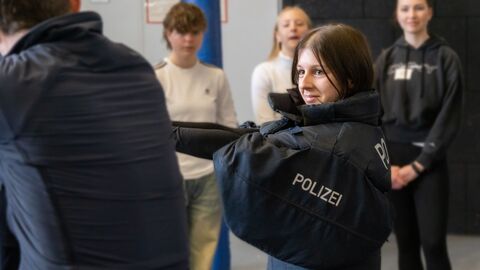 Eine junge Frau trägt polizeiliche Schutzausstattung